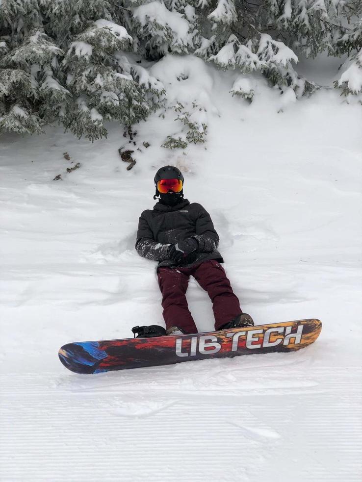 Me lying down in some snow wearing my snowboarding gear